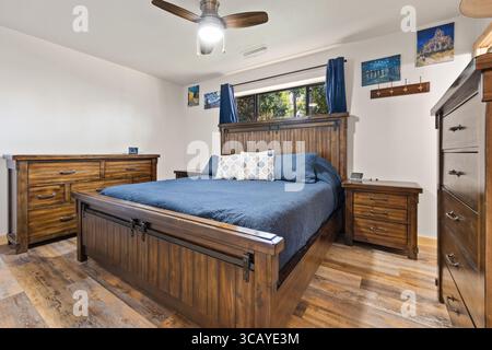 Une chambre confortable avec un lit confortable, une commode élégante, une table de chevet pratique et un ventilateur de plafond de refroidissement pour les nuits chaudes Banque D'Images
