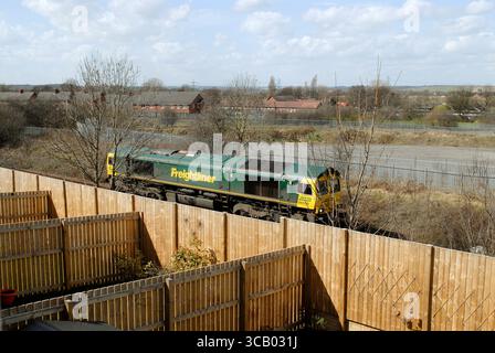 Une locomotive diesel de la classe 66 passe à proximité de jardins urbains sur le Leeds à Castleford ligne de chemin de fer dans le West Yorkshire Banque D'Images