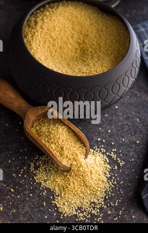 Couscous cru en cuillère sur une table noire. Banque D'Images