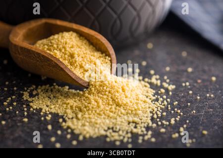 Couscous cru en cuillère sur une table noire. Banque D'Images