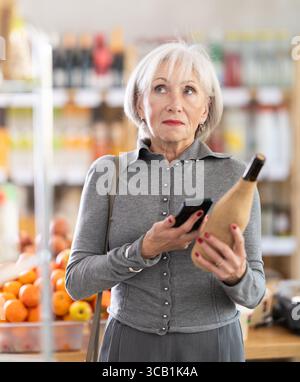 Femme âgée scannant le code qr du vin Banque D'Images