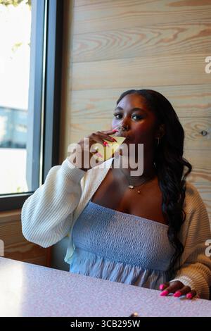 Portrait d'une femme noire buvant un mimosa Banque D'Images