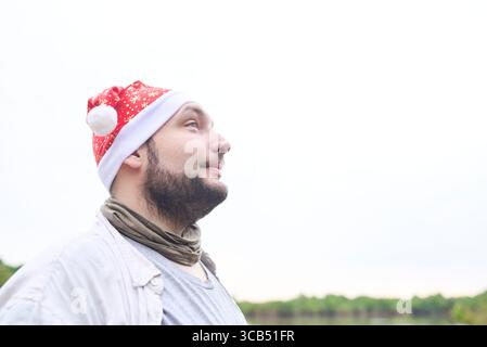 Portrait d'un jeune homme hispanique portant un chapeau de Noël à l'extérieur, dans un paysage naturel. Banque D'Images