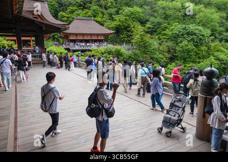 Groupe de touristes explorant la scène historique au temple bouddhiste Kiyomizu-dera, entouré d'une végétation luxuriante, quartier Higashiyama, Kyoto, Japon Banque D'Images
