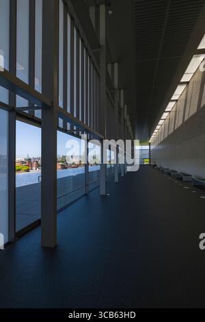 Un couloir spacieux et moderne avec de grandes fenêtres en verre et un design élégant, capturant l'élégance architecturale et la lumière naturelle dans l'aile Heisei Chishinkan Banque D'Images