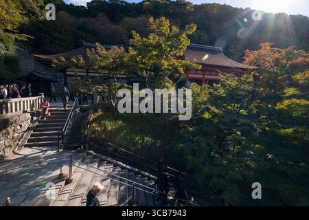 Une vue panoramique sur le temple bouddhiste Kiyomizu-dera entouré d'arbres d'automne luxuriants, avec la lumière du soleil et les visiteurs, Kyoto, Japon Banque D'Images