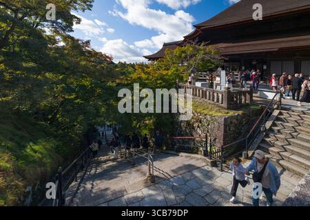 Touristes explorant l'escalier du temple bouddhiste Kiyomizu-dera entouré d'une végétation luxuriante sous un ciel bleu, Kyoto, Japon Banque D'Images