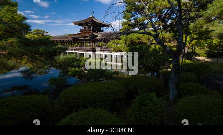 Heian Jingu Taiheikaku Pavillon reflétant dans un étang tranquille, entouré de verdure luxuriante et d'arbres vibrants sous un ciel bleu clair, mettant en valeur harmon Banque D'Images