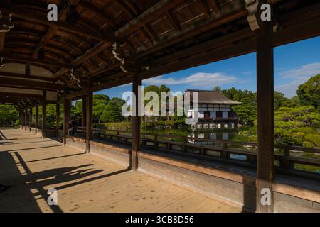 Magnifique pavillon Heian Jingu Taiheikaku en bois avec passerelle ombragée et vue, entouré d'une végétation luxuriante et d'un étang tranquille. Jardin du sanctuaire Heian, Banque D'Images