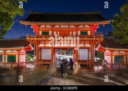 La porte de Yasaka Jinja Nishiromon a été magnifiquement éclairée pendant la soirée, mettant en valeur l'architecture culturelle. Les personnes en mouvement capturent le vivant et vivant Banque D'Images