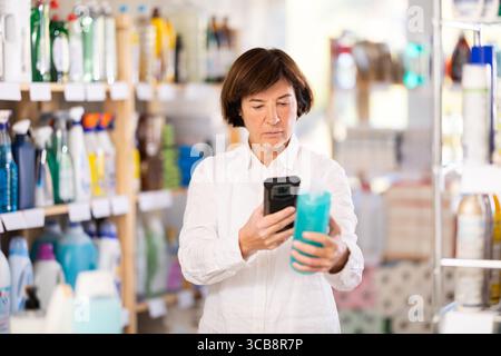 Femme âgée scannant le code qr pour shampooing ou gel douche Banque D'Images