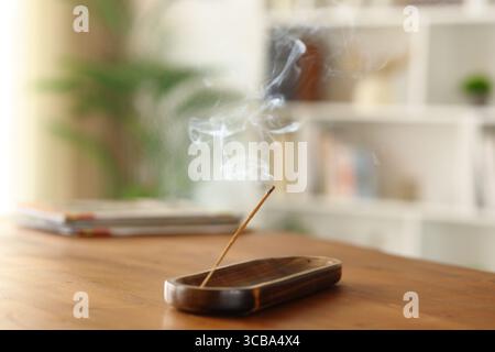 Gros plan portrait de bâton d'encens brûlant sur une table en bois à la maison Banque D'Images