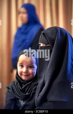 22 octobre 2016 : une mère musulmane portant une burqua couvrant le visage tient son fils en vêtements traditionnels du moyen-Orient dans une mosquée d'Anaheim, CALIFORNIE. Note femme en arrière-plan portant un hijab, le foulard traditionnel de la tête féminine musulmane. (Crédit image : © Spencer Grant/ZUMA Press Wire) Banque D'Images