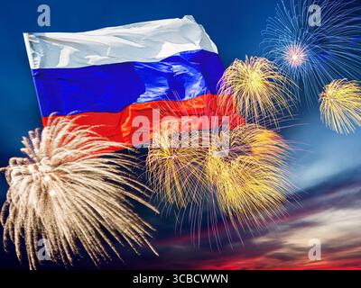 Agitant le drapeau russe contre le ciel du coucher du soleil avec des feux d'artifice éclatants colorés. Concept de jour de victoire ou d'indépendance Banque D'Images