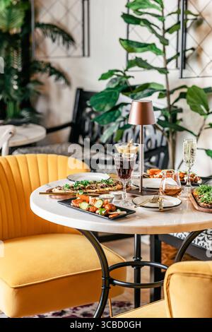 Table de restaurant élégante avec boissons, hors-d'œuvre et décoration. Banque D'Images