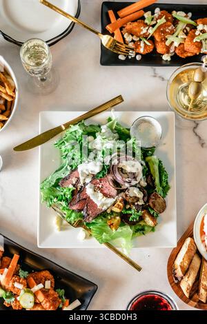 Vue de haut en bas du repas gastronomique partagé avec salades, martini, boissons. Banque D'Images