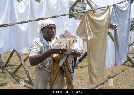 Dhobi Ghat, lessive en plein air à Kochi, Inde, vêtements nettoyés accrochés sur la ligne de vêtements, l'homme collecte les draps de lit secs et le linge, 20.03.2025 Banque D'Images