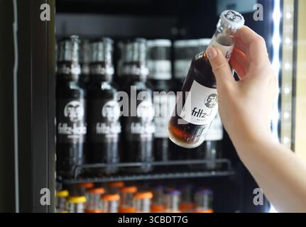 Hambourg, Allemagne. 07 août 2025. Un employé prend la main pour une bouteille de Fritz-Kola dans un réfrigérateur au siège de la société Fritz-Kola GmbH. Crédit : Marcus Brandt/dpa/Alamy Live News Banque D'Images