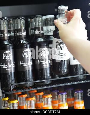 Hambourg, Allemagne. 07 août 2025. Un employé prend la main pour une bouteille de Fritz-Kola dans un réfrigérateur au siège de la société Fritz-Kola GmbH. Crédit : Marcus Brandt/dpa/Alamy Live News Banque D'Images