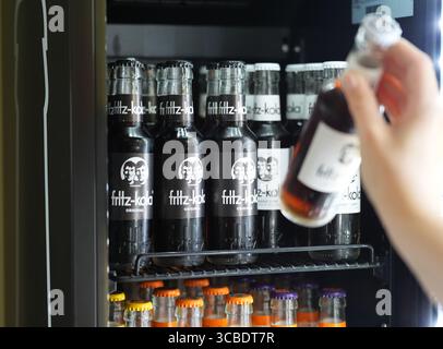 Hambourg, Allemagne. 07 août 2025. Un employé prend la main pour une bouteille de Fritz-Kola dans un réfrigérateur au siège de la société Fritz-Kola GmbH. Crédit : Marcus Brandt/dpa/Alamy Live News Banque D'Images