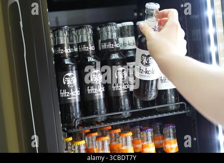 Hambourg, Allemagne. 07 août 2025. Un employé prend la main pour une bouteille de Fritz-Kola dans un réfrigérateur au siège de la société Fritz-Kola GmbH. Crédit : Marcus Brandt/dpa/Alamy Live News Banque D'Images