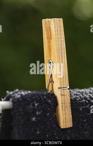 Gros plan d'une épingle de corde à linge en bois tenir une chemise noire sur une ligne Banque D'Images