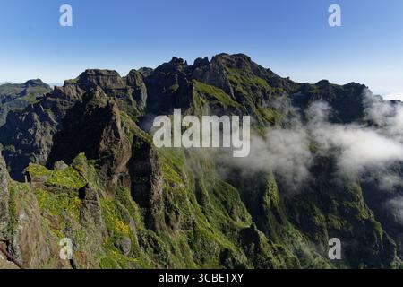 Vue aérienne des pics déchiquetés perce le ciel, leurs pentes verdoyantes drapées dans la brume éthérée, une symphonie de la grandeur de la nature, Madère, Portugal. Banque D'Images