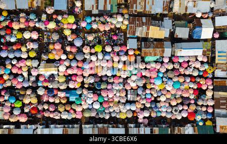 Vue aérienne d'une mer vibrante de parapluies colorés pop contre les textures rustiques des toits ondulés, créant une mosaïque animée de commerce, Jos, PL Banque D'Images