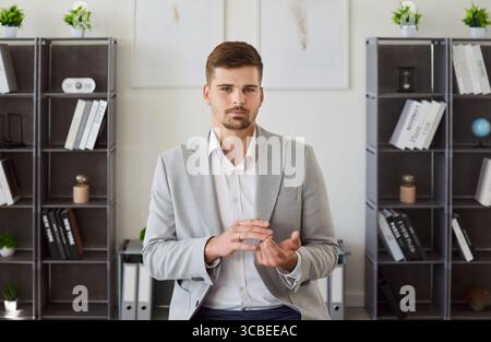 Portrait d'homme d'affaires sérieux faisant des gestes et regardant la caméra pendant la conversation formelle. Banque D'Images