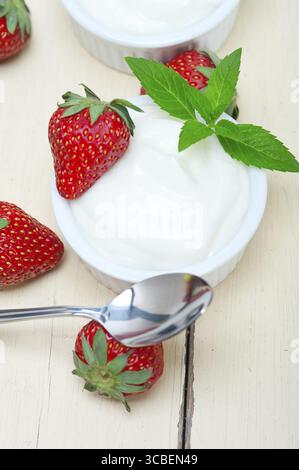 Yaourt grec biologique et fraise sur table en bois rustique blanc Banque D'Images