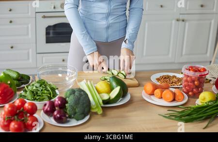 Gros plan de femme coupant le concombre dans la cuisine Banque D'Images