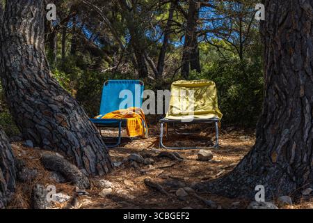 Deux chaises longues colorées situées dans la forêt à l'ombre des arbres, prenant place sur la plage par les touristes en Croatie Banque D'Images