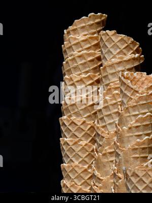 Pile de cônes de crème glacée gaufrés vides isolés sur fond noir Banque D'Images