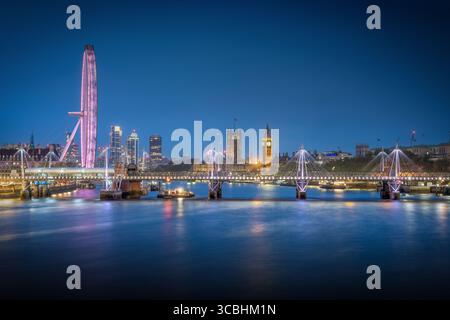 Vue imprenable sur le pont de Waterloo à Londres, avec Big Ben, Westminster Palace et le London Eye illuminés dans le ciel crépusculaire. Banque D'Images