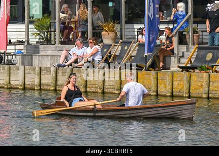 West Bay, Dorset, Royaume-Uni. 8 août 2025. Météo britannique. Les vacanciers ayant du plaisir à ramer un bateau le long de la rivière Brit comme ils apprécient le soleil brûlant de l'après-midi à la station balnéaire de West Bay dans le Dorset pendant les vacances d'été. Crédit photo : Graham Hunt/Alamy Live News Banque D'Images