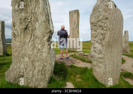 Visiteurs se dresse parmi les anciennes pierres de Calanish (gaélique : Calanais), île de Lewis, Hébrides extérieures, Écosse. Banque D'Images