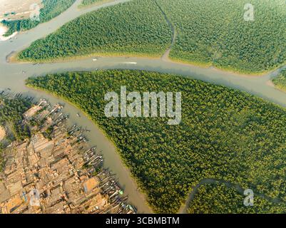 Vue aérienne des voies navigables complexes creusant à travers des forêts denses de mangrove le long d'une colonie avec des bateaux amarrés, Sundarban, Khulna Division, Bangladesh. Banque D'Images