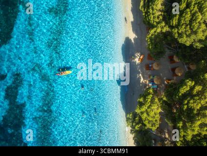 Vue aérienne de kayak, mer bleue, plage de sable, arbres et parasols Banque D'Images