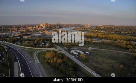 Vue aérienne de la rivière Maumee serpentant à travers la ville, reflétant les teintes douces de la lumière de fin d'après-midi, contrastées par la ligne d'horizon imposante, à Banque D'Images