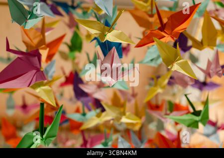 Des centaines de grues en origami colorées accrochées avec des cordes au plafond. Banque D'Images