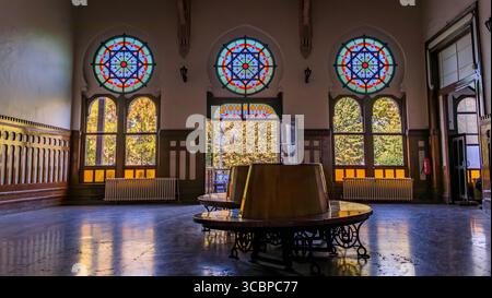 Istanbul, Turquie - 10 novembre 2023 : Grand intérieur de l'historique terminal Sirkeci avec des bancs en bois ornés et des vitraux à motifs étoilés Banque D'Images