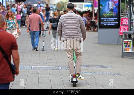 Elektro-Tretroller in öffentlicher Kritik Eine person fährt mit einen sogenannten E-Scooter quer quer durch die Fußgänger auf einer Einkaufsstraße. Essen Nordrhein-Westfalen Deutschland Kettwiger Straße *** scooter électrique dans la critique publique Une personne conduit un soi-disant e-scooter à travers les piétons dans une rue commerçante Essen Rhénanie du Nord-Westphalie Allemagne Kettwiger Straße Banque D'Images