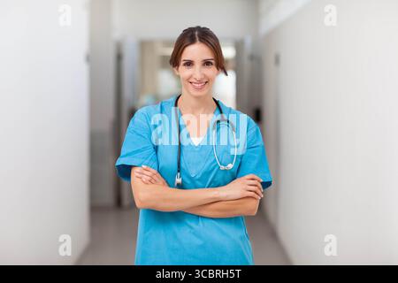 Femme professionnelle de la santé croisant les bras dans le couloir de l'hôpital portant des gommages bleus et stéthoscope Banque D'Images