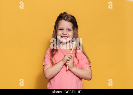 Une fille heureuse tient une brosse à dents dans ses mains. Un tir isolé. Odontologie pédiatrique Banque D'Images