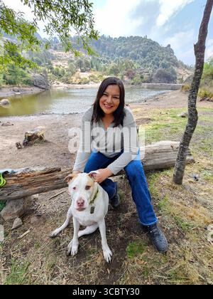 Une femme adulte latina passe du temps à l'extérieur avec son chien de soutien émotionnel comme thérapie pour le stress et l'anxiété Banque D'Images