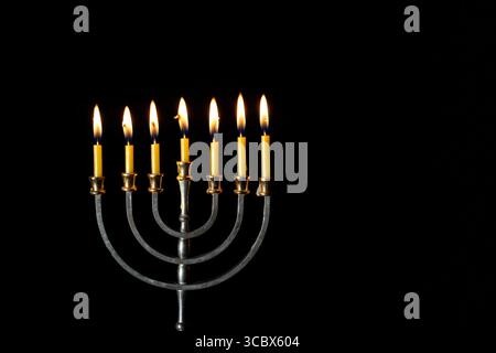 Hanukkah menorah avec des bougies allumées sur fond noir. Symbole juif. Banque D'Images