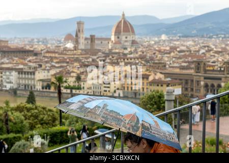 Florence, Italie - 10 mai 2025 : personnes avec un parapluie souvenir montrant des monuments italiens, photographiées depuis Piazzale Michelangelo Banque D'Images
