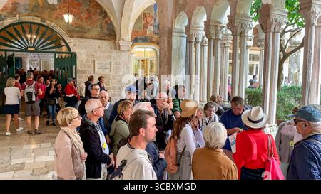 Dubrovnik, Croatie. Août 09,2025. Un guide touristique conduit un groupe de touristes à travers le cloître bondé du monastère franciscain et de l'église, l'un des sites les plus visités de la vieille ville fortifiée. Depuis 2017, la ville la plus célèbre de Croatie, également connue pour sa réputation de « ville la plus surpeuplée du monde », a mis en œuvre de nombreuses mesures pour faire face à l'afflux touristique, y compris des efforts pour organiser les flux de visiteurs en étalant les créneaux horaires de visite pour les principaux types de tourisme : les passagers de bateaux de croisière, les groupes de voyages en autocar et les touristes séjournant dans les logements de la ville. Crédit : Kevin Izorce/Alamy Live News Banque D'Images