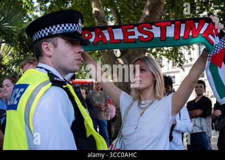 Une femme avec une écharpe palestinienne regarde directement un policier présent alors qu'ils arrêtent des manifestants pacifiques qui s'opposent au génocide et soutiennent le groupe d'action directe interdit Palestine action et qui sont venus sur la place du Parlement en toute connaissance de cause, ils seraient arrêtés et risqueraient d'être condamnés à de longues peines de prison pour leur opposition à la crise humanitaire en cours à Gaza le 9 août 2025 à Londres, Royaume-Uni. De nombreux manifestants ont également manifesté leur soutien aux personnes arrêtées pour avoir soutenu Palestine action que le gouvernement britannique a récemment interdite comme organisation terroriste. Metropolita Banque D'Images