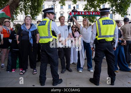 Une femme avec une écharpe palestinienne regarde directement un policier présent alors qu'ils arrêtent des manifestants pacifiques qui s'opposent au génocide et soutiennent le groupe d'action directe interdit Palestine action et qui sont venus sur la place du Parlement en toute connaissance de cause, ils seraient arrêtés et risqueraient d'être condamnés à de longues peines de prison pour leur opposition à la crise humanitaire en cours à Gaza le 9 août 2025 à Londres, Royaume-Uni. De nombreux manifestants ont également manifesté leur soutien aux personnes arrêtées pour avoir soutenu Palestine action que le gouvernement britannique a récemment interdite comme organisation terroriste. Metropolita Banque D'Images